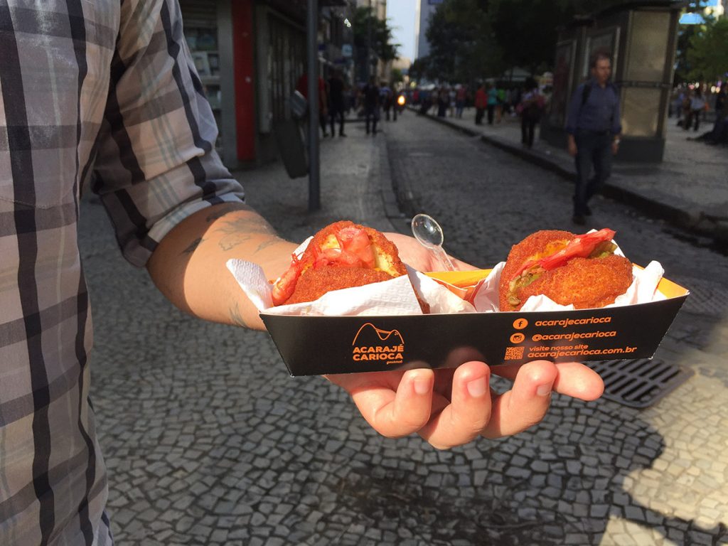 Embalagem do Foodtruck Acarajé Carioca, com duas acarajés para degustação nos eventos